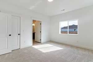 Unfurnished bedroom featuring light colored carpet and connected bathroom