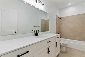 Bathroom featuring vanity, bathtub / shower combination, light tile patterned floors, and recessed lighting