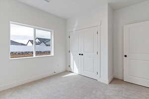 Unfurnished bedroom featuring light colored carpet and a closet