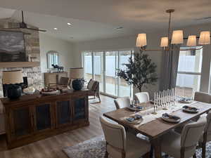 Photos are of staged model home.  Dining room with vaulted ceiling, a chandelier, a stone fireplace, wood finished floors, and recessed lighting