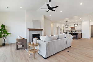 Living area featuring a ceiling fan, light wood finished floors, a tiled fireplace, and recessed lighting