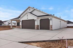 View of front of property featuring a garage, concrete driveway, and stone siding