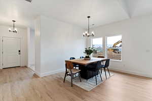 Dining space with suspended lighting and light wood-type flooring