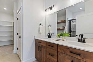 Full bath featuring double vanity, recessed lighting, a shower stall, a walk in closet, and light tile patterned floors