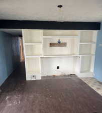 Unfurnished living room featuring a textured ceiling and built in features