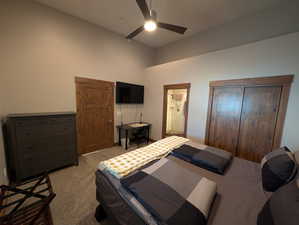 Carpeted bedroom featuring a ceiling fan, ensuite bath, and a towering ceiling