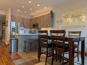 Kitchen with light wood-style flooring, recessed lighting, appliances with stainless steel finishes, a breakfast bar area, and a peninsula