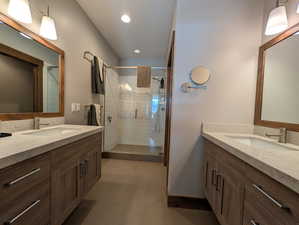 Full bathroom featuring two vanities, a shower stall, and recessed lighting
