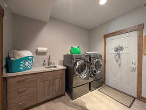 Washroom with washing machine and dryer, light wood-style flooring, and cabinet space