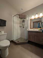 Full bath featuring vanity, dark tile patterned floors, and a stall shower