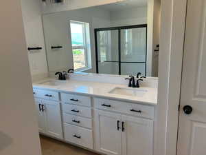 Full bathroom featuring double vanity and a shower stall