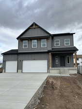 View of front of property with board and batten siding, covered porch, driveway, and roof with shingles