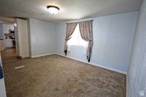 Spare room with dark carpet and a textured ceiling
