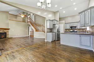 Kitchen with open floor plan, dark wood-style floors, stainless steel appliances, recessed lighting, and a stone fireplace