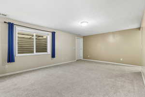 Carpeted spare room featuring baseboards and a textured ceiling