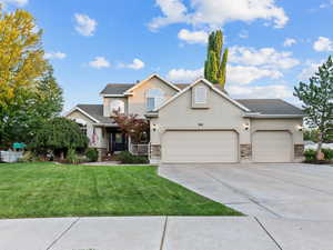 Traditional home featuring stucco siding, concrete driveway, a garage, and stone siding