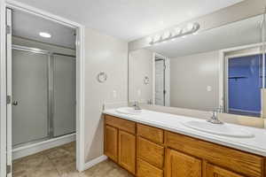 Full bathroom with a stall shower, double vanity, and light tile patterned floors