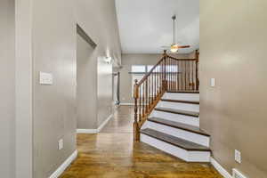 Stairway with wood finished floors and ceiling fan