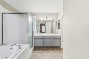 Bathroom with double vanity, a jetted tub, a stall shower, and light tile patterned floors