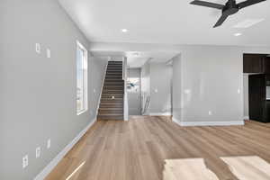 Unfurnished living room with light wood-style flooring, a ceiling fan, stairs, and recessed lighting