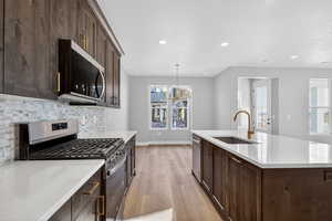 Kitchen featuring dark brown cabinetry, stainless steel appliances, pendant lighting, recessed lighting, and light wood-type flooring