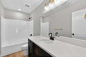 Bathroom featuring vanity, washtub / shower combination, and light wood-style flooring