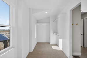 Walk in closet with light carpet and lofted ceiling