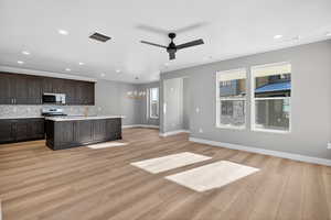 Kitchen featuring a chandelier, light wood-style floors, appliances with stainless steel finishes, ceiling fan, and a kitchen island with sink