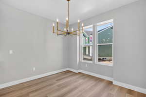 Unfurnished dining area featuring a chandelier and light wood finished floors
