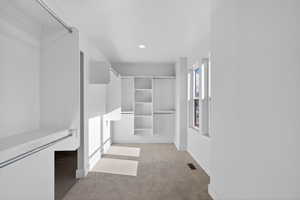 Walk in closet with light colored carpet