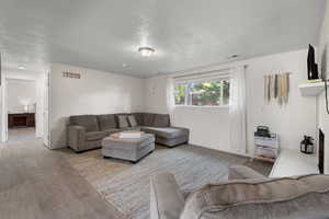 Living room with a textured ceiling, a fireplace, and wood finished floors