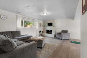 Living area featuring a textured ceiling, a fireplace, and wood finished floors