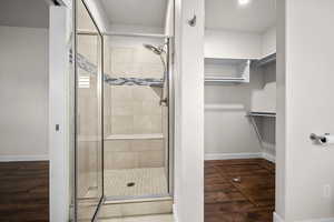Bathroom with a stall shower, dark wood finished floors, and a spacious closet