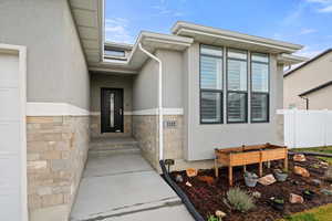 View of exterior entry featuring stone siding and stucco siding
