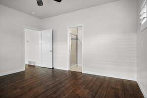 Unfurnished bedroom with dark wood-style flooring, a ceiling fan, and connected bathroom