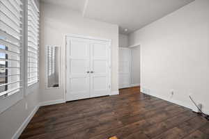 Unfurnished bedroom with dark wood-style flooring and a closet