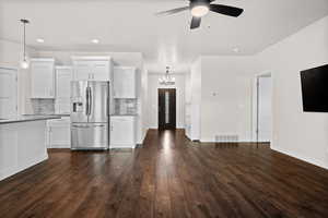 Kitchen with stainless steel fridge with ice dispenser, white cabinetry, hanging light fixtures, tasteful backsplash, and recessed lighting