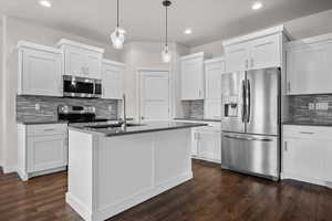 Kitchen featuring appliances with stainless steel finishes, white cabinets, tasteful backsplash, hanging light fixtures, and recessed lighting