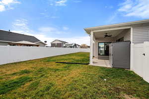 Fenced backyard with a ceiling fan, a patio area, and a residential view