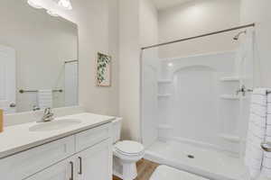 Bathroom featuring vanity, a stall shower, and light wood-style flooring