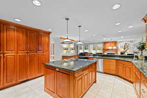 Kitchen featuring dark stone counters, light tile patterned floors, dishwasher, a kitchen island, and recessed lighting