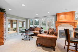 Living area featuring a glass covered fireplace, light carpet, recessed lighting, and plenty of natural light