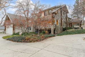 View of home's exterior featuring stone siding, driveway, and a garage