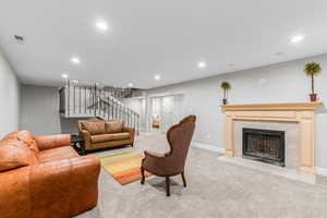Carpeted living area with stairway, recessed lighting, and a tile fireplace