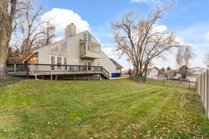 Rear view of property featuring a wooden deck, stucco siding, a fenced backyard, and stairs