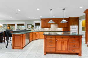 Kitchen featuring a kitchen bar, a kitchen island, light tile patterned flooring, pendant lighting, and recessed lighting
