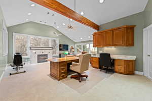 Home office with light colored carpet, a fireplace, recessed lighting, beamed ceiling, and high vaulted ceiling