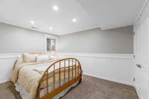 Carpeted bedroom featuring wainscoting, recessed lighting, crown molding, and a decorative wall