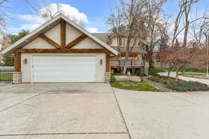 View of front of property featuring stucco siding, concrete driveway, stone siding, and a garage
