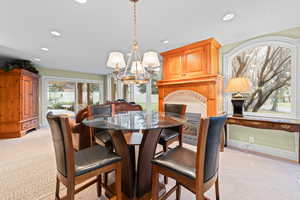 Dining area featuring light colored carpet, a fireplace, a chandelier, and recessed lighting